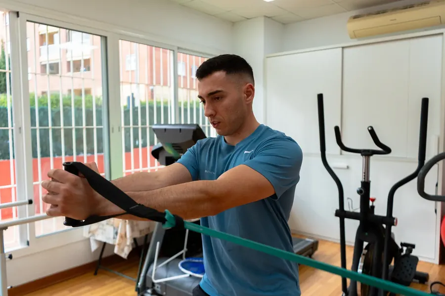 Ejercicio de fuerza con goma elástica supervisado por el entrenador