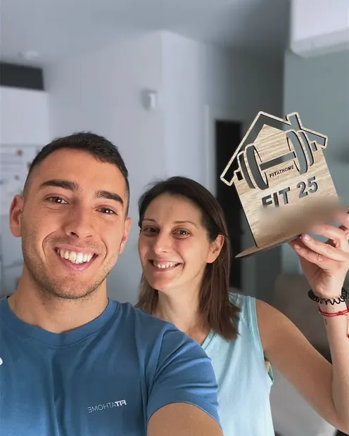 Clienta con su placa FIT 25 en el pasillo de su casa